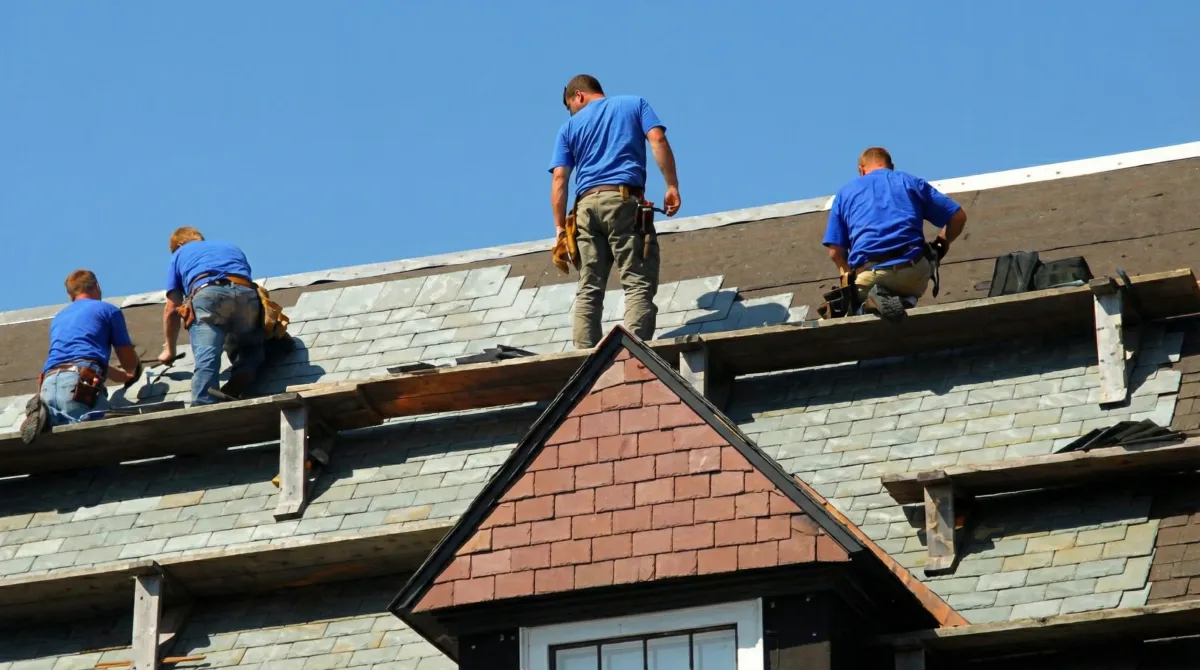 Roof replacement in progress with a team of professional contractors installing new shingles on a residential home in Cambridge, MA